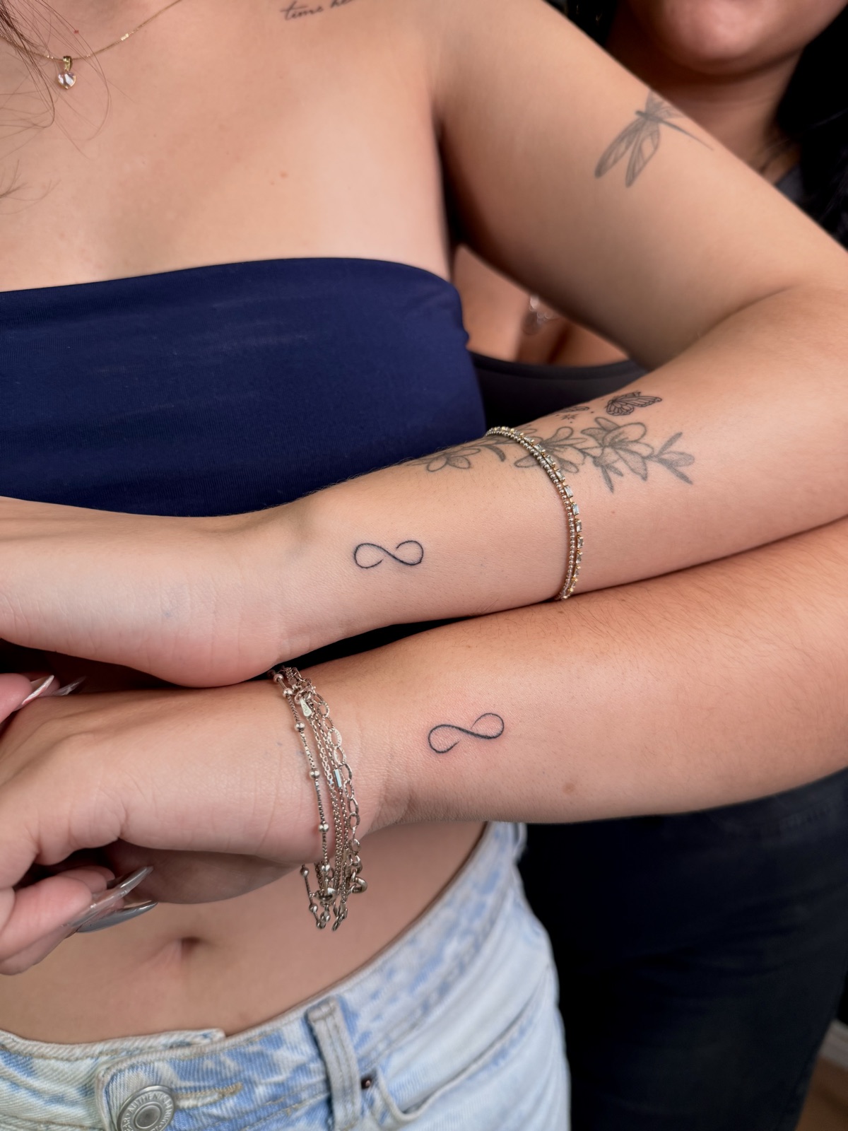 Símbolo do infinito em traço fino, feito em duas pessoas, no punho. Por Dudis (Maria Eduarda Freitas), na ADV Tattoo.